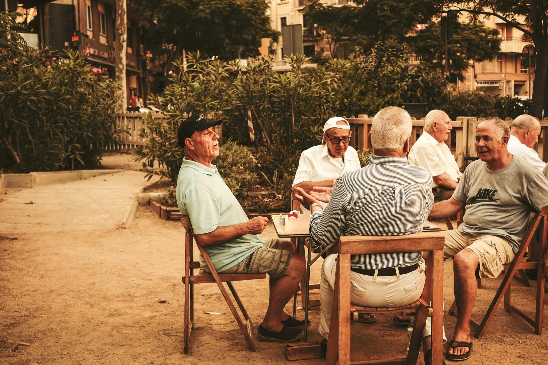 Personas mayores sentadas a una mesa jugando al dominó